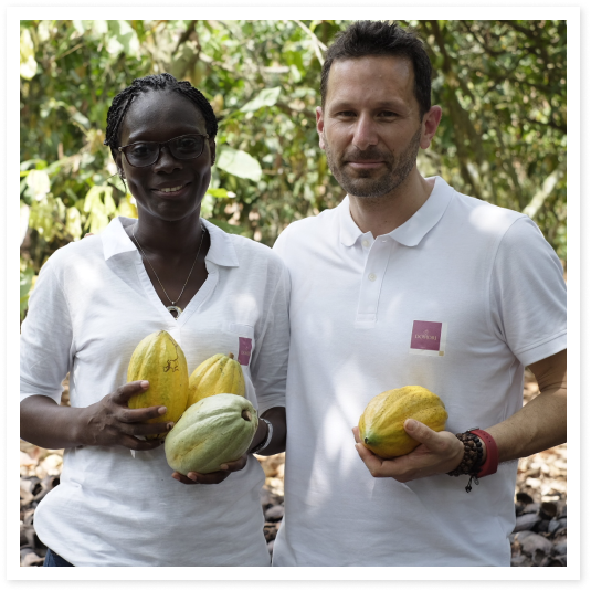 Two people holding cacao pods.